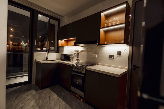 Kitchen at night with under-cabinet lighting and wine glasses on the shelf