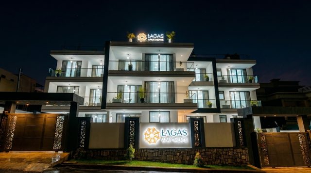 Lagas Apartments at night, the building lit up with the signage glowing